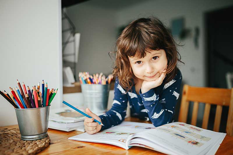 Elementary School student writing in her workbook for her homeschool class